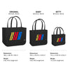 Three black Bogg bags with colorful stripes labeled 'Original', 'Baby', and 'Bitty' on a white background.